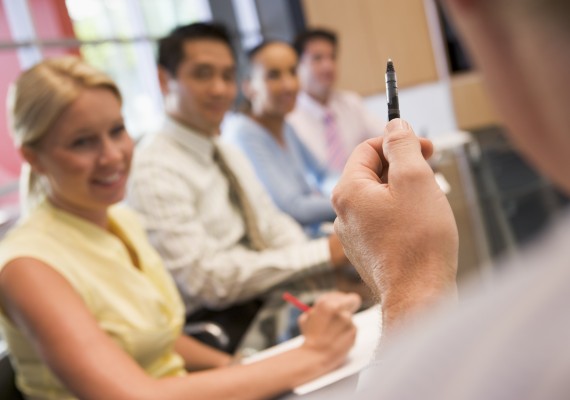 Five businesspeople at boardroom table with focus on businessman